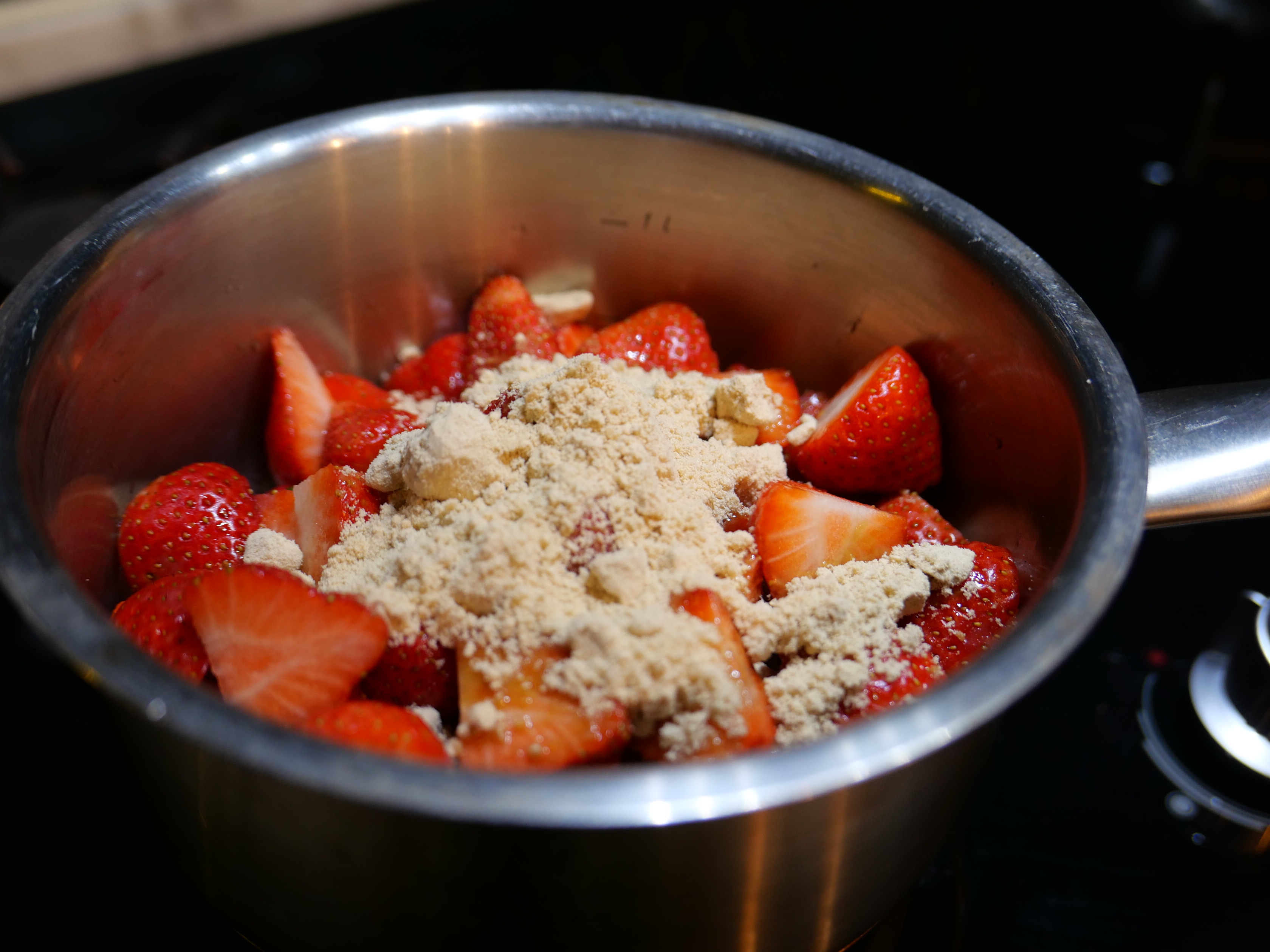 將洗好的草莓放入鍋中，加入糖。
