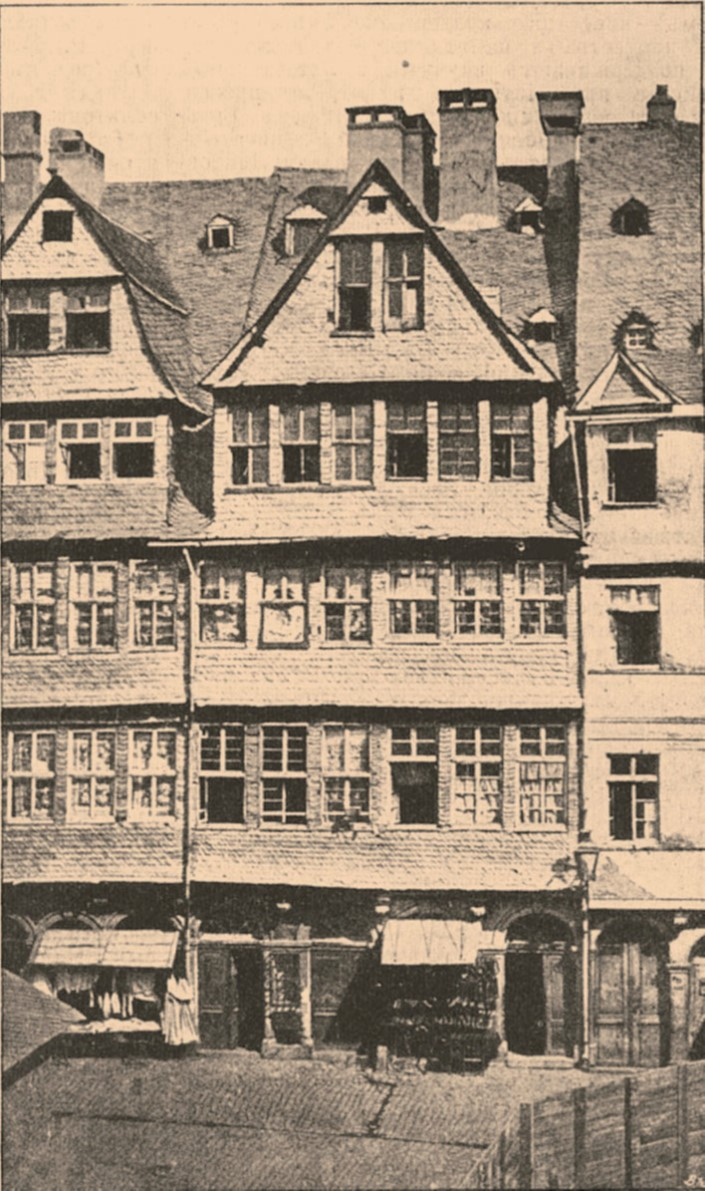 （圖說：位於法蘭克福猶太巷的羅斯柴爾德住宅「綠盾」（zum grünen Schild）。照片拍攝於一八六九年，當時大部分的街道都被拆除。邁爾．阿姆謝爾於一七八五年收購了中央山牆建築的左半邊。）