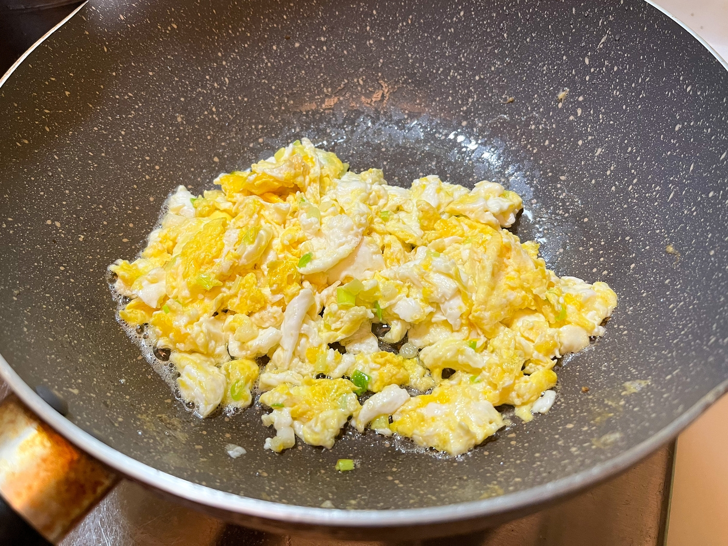 等到油熱到接近冒煙，打入兩顆蛋、下蔥白，等約三秒後把蛋快速攪在一起、剁碎。接下來的過程要繼續保持大火。